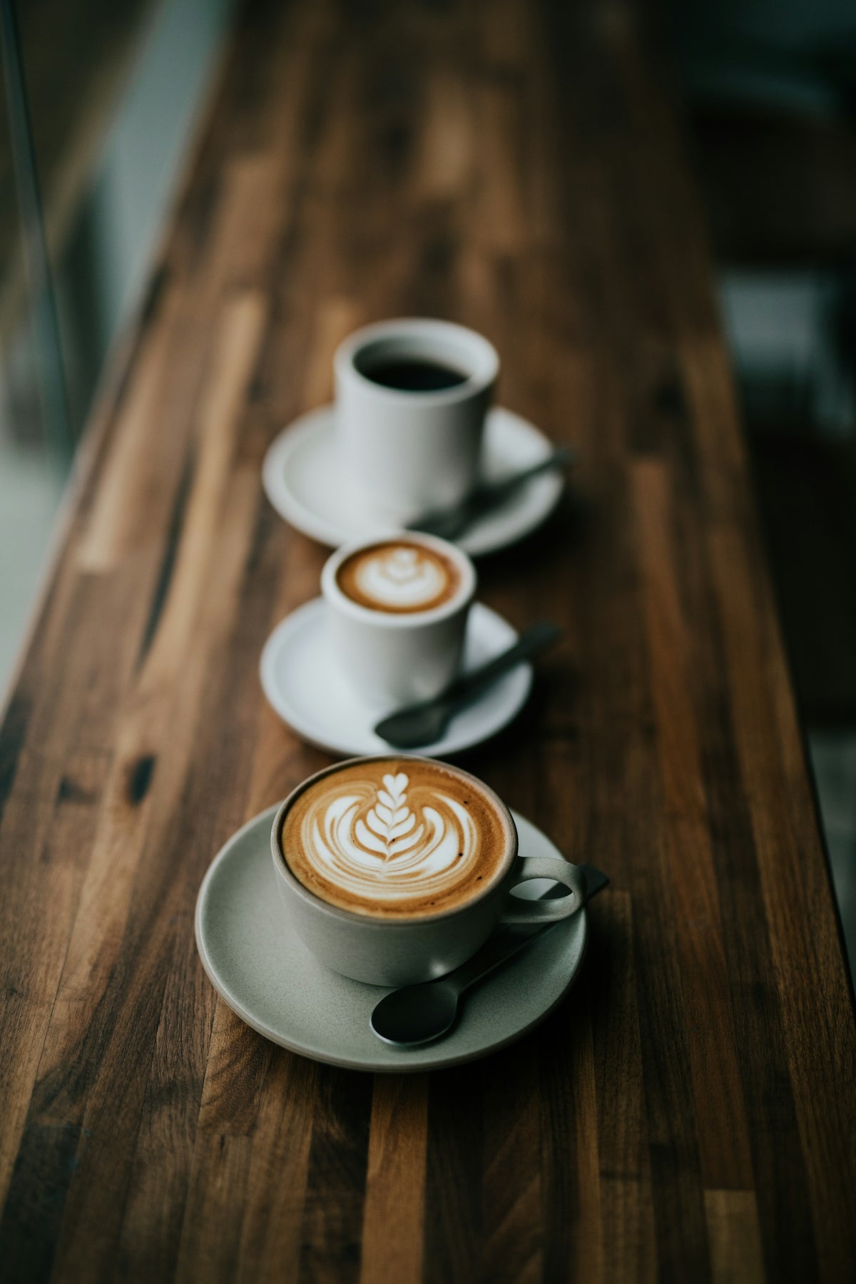 木目が美しいカウンターに、ラテアートの美しい3杯のコーヒーが並ぶ。静かで洗練された朝のひととき。