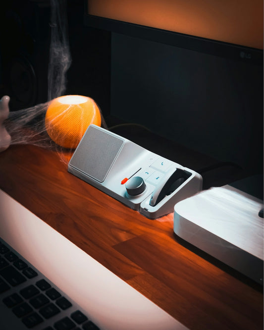 A person's hand reaching for an orange on a desk