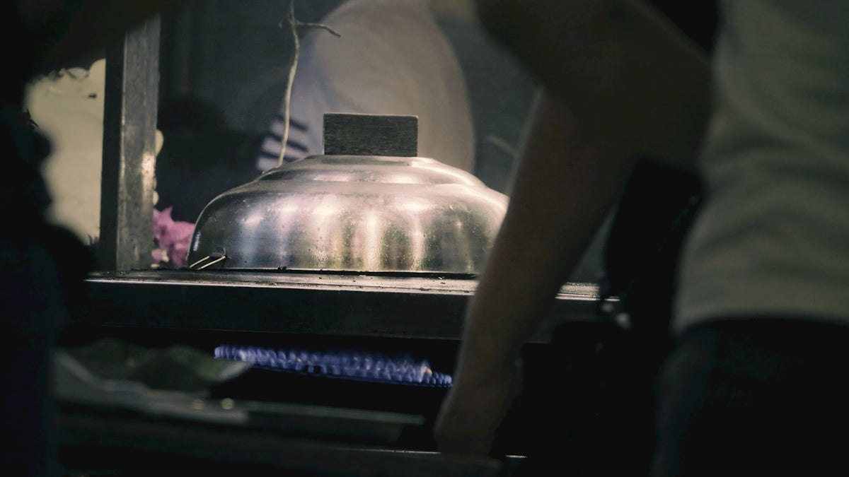 People gathered around a steaming food cart at night.