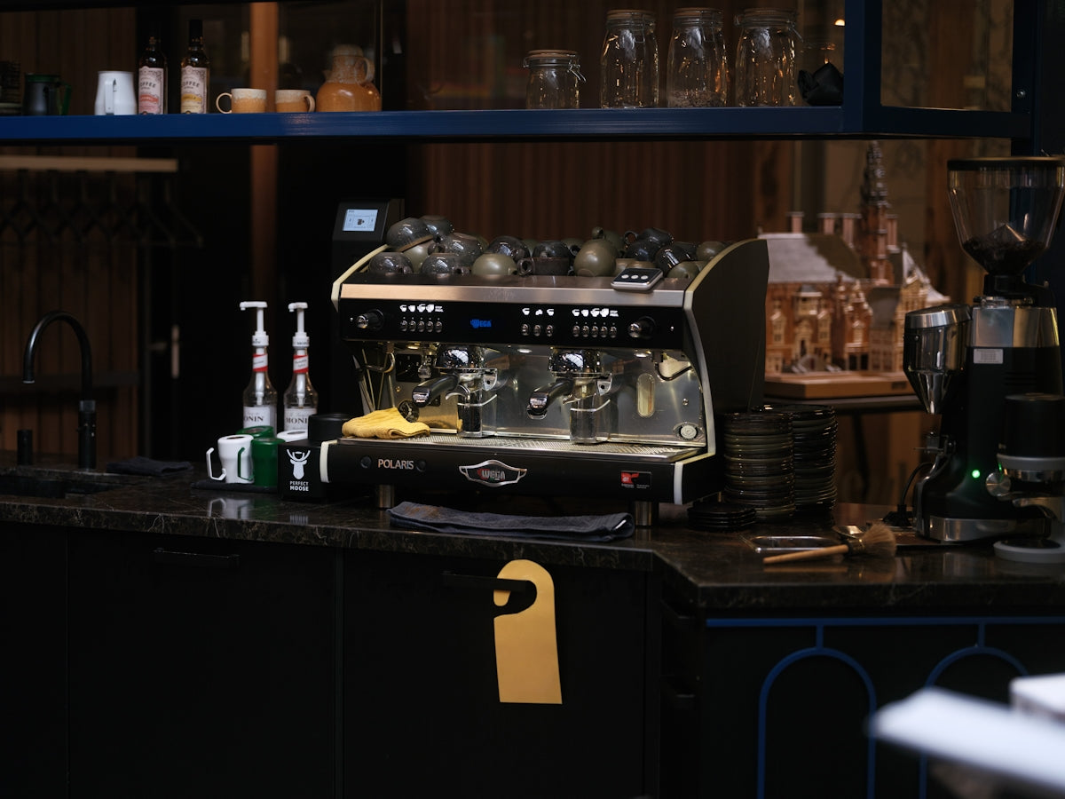 プロフェッショナルなカフェカウンター。WEGA POLARISエスプレッソマシンが中心に鎮座し、整然と並ぶ器具と温かみのある照明が職人技を予感させる。